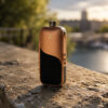 Tan AirVape Legacy Core positioned on rocks beside a lake