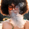 Outdoor lifestyle image of a woman taking a draw from the Ghost 2 vaporizer