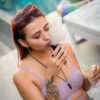 Woman using a portable Dr. Dabber Ghost 2 wax vaporizer outside